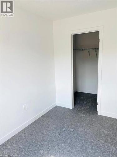 Unfurnished bedroom with a spacious closet and dark colored carpet - 7 Pin Oak Common, Cambridge, ON - Indoor Photo Showing Other Room