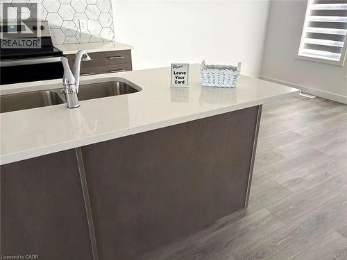 Kitchen with dark brown cabinetry, stainless steel range with electric cooktop, light stone counters, and light wood-style floors - 7 Pin Oak Common, Cambridge, ON - Indoor Photo Showing Kitchen With Double Sink