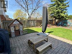 Spacious outdoor patio featuring paver stones, a manicured lawn, and mature trees - 