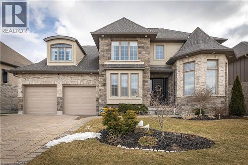 View of front of house with a shingled roof, driveway, stone siding, and a front lawn - 2719 Torrey Pines Way, London, ON - Outdoor With Facade