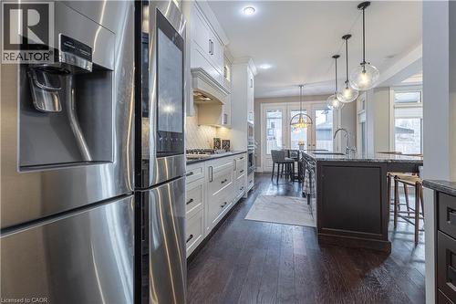 Dual tone kitchen with stainless steel appliances, dual tone cabinetry, dark wood-style flooring, dark stone counters, and a kitchen breakfast bar - 2719 Torrey Pines Way, London, ON - Indoor Photo Showing Kitchen With Upgraded Kitchen