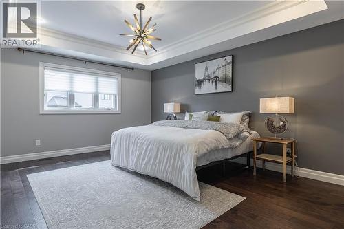 Bedroom featuring a tray ceiling, dark wood-style floors, hanging lights, and crown molding - 2719 Torrey Pines Way, London, ON - Indoor Photo Showing Bedroom