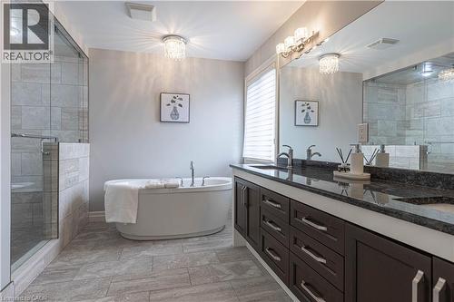 Bathroom with a stall shower, double vanity, a freestanding tub, and light stone finish flooring - 2719 Torrey Pines Way, London, ON - Indoor Photo Showing Bathroom
