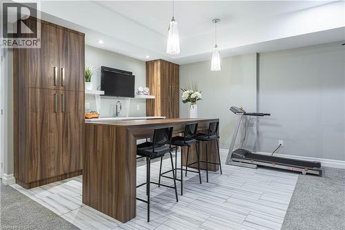 Bar area featuring wood finish cabinetry, open shelves, modern cabinets, decorative light fixtures, and butcher block counters - 2719 Torrey Pines Way, London, ON - Indoor Photo Showing Other Room