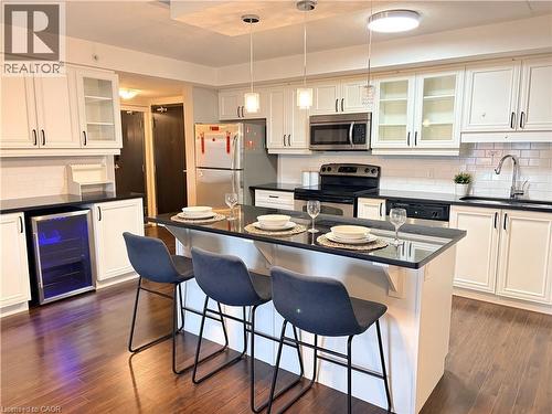 Kitchen featuring glass insert cabinets, decorative backsplash, a kitchen bar, and white cabinetry - 776 Laurelwood Drive Unit# 406, Waterloo, ON - Indoor Photo Showing Kitchen With Stainless Steel Kitchen