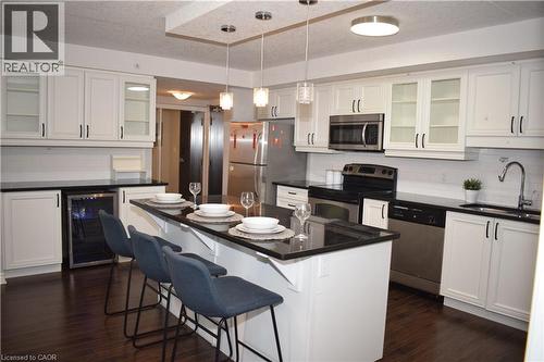 Kitchen featuring glass insert cabinets, backsplash, stainless steel appliances, a breakfast bar area, and white cabinetry - 776 Laurelwood Drive Unit# 406, Waterloo, ON - Indoor Photo Showing Kitchen With Stainless Steel Kitchen With Upgraded Kitchen