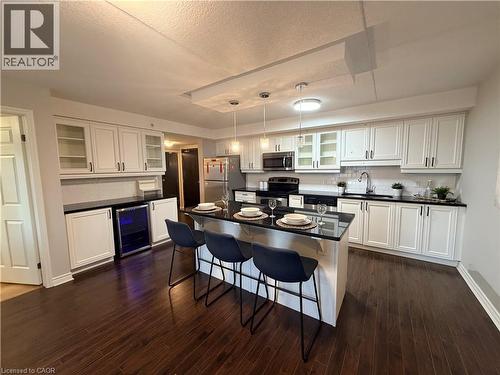 Kitchen featuring glass fronted cabinets, a breakfast bar, stainless steel appliances, white cabinetry, and a textured ceiling - 776 Laurelwood Drive Unit# 406, Waterloo, ON - Indoor Photo Showing Kitchen