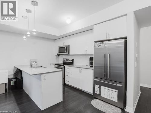 Kitchen with a peninsula, stainless steel appliances, white cabinets, and backsplash - 1206 Main Street E Unit# 113, Milton, ON - Indoor Photo Showing Kitchen