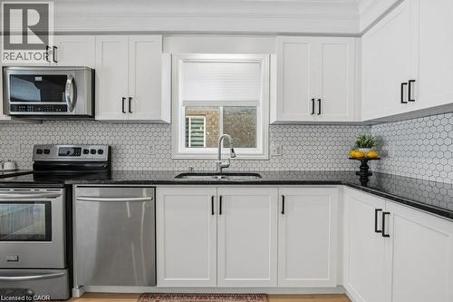 Upgraded kitchen with granite counterops, new cupboard doors, and backsplash - 26 Helena Feasby Street, Kitchener, ON - Indoor Photo Showing Kitchen With Double Sink
