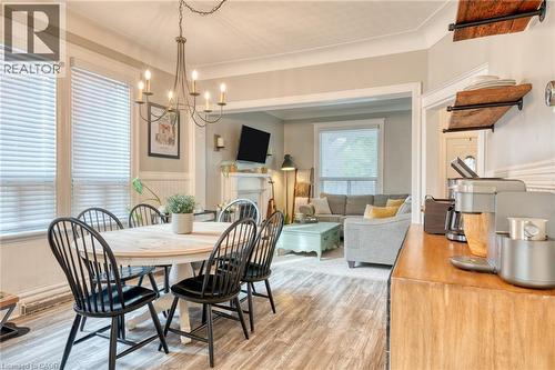 Dining area featuring wainscoting, light wood-style floors, suspended lighting, and a fireplace - 37 Cliff Avenue, Hamilton, ON - Indoor Photo Showing Dining Room