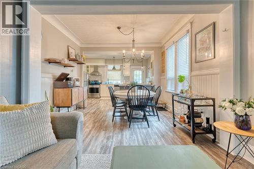 Dining room featuring a wainscoted wall, light wood-type flooring, suspended lighting, and crown molding - 37 Cliff Avenue, Hamilton, ON - Indoor