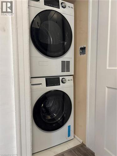 Laundry area with stacked washer and dryer and wood finished floors - 37 Cliff Avenue, Hamilton, ON - Indoor Photo Showing Laundry Room