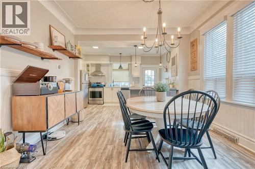 Dining space featuring wainscoting, hanging lights, light wood-style flooring, crown molding, and a decorative wall - 37 Cliff Avenue, Hamilton, ON - Indoor Photo Showing Dining Room