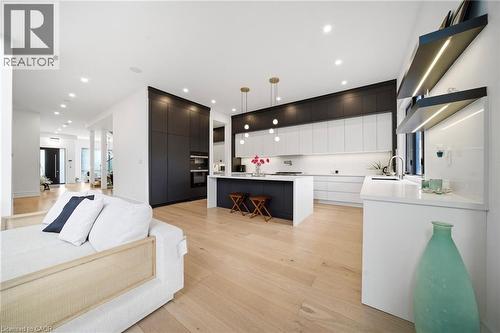 Dual tone kitchen featuring a kitchen breakfast bar, open floor plan, light wood-style flooring, modern cabinets, and a kitchen island - 2556 Glengarry Road, Mississauga, ON - Indoor