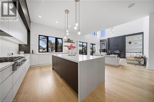 Dual tone kitchen featuring modern cabinets, two tone cabinetry, a center island, light wood-style floors, and stainless steel gas stovetop - 2556 Glengarry Road, Mississauga, ON - Indoor Photo Showing Kitchen With Upgraded Kitchen