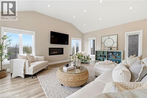 Living area featuring vaulted ceiling, light wood-style floors, a glass covered fireplace, and recessed lighting - 39 Mill Race Crescent, St. Jacobs, ON - Indoor Photo Showing Living Room With Fireplace