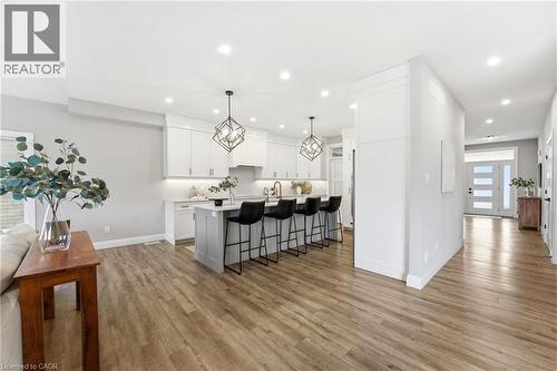 Kitchen featuring a kitchen bar, a large island with sink, light wood-type flooring, white cabinets, and hanging light fixtures - 39 Mill Race Crescent, St. Jacobs, ON - Indoor Photo Showing Kitchen With Upgraded Kitchen
