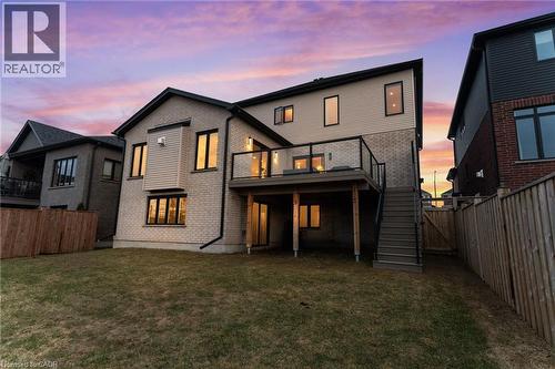 Back of property at dusk featuring a fenced backyard, a wooden deck, brick siding, and a gate - 39 Mill Race Crescent, St. Jacobs, ON - Outdoor With Deck Patio Veranda