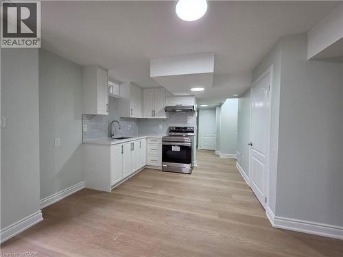 Kitchen with stainless steel electric range, tasteful backsplash, white cabinetry, and light wood-style flooring - 367 Equestrian Way Unit# Basement, Cambridge, ON - Indoor Photo Showing Kitchen
