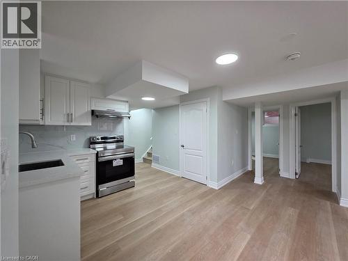 Kitchen featuring stainless steel electric stove, white cabinetry, light stone countertops, tasteful backsplash, and light wood-style flooring - 367 Equestrian Way Unit# Basement, Cambridge, ON - Indoor Photo Showing Kitchen