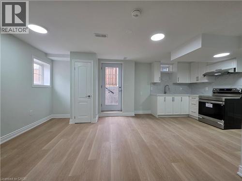 Kitchen featuring stainless steel electric stove, light countertops, white cabinets, backsplash, and light wood-style floors - 367 Equestrian Way Unit# Basement, Cambridge, ON - Indoor Photo Showing Kitchen