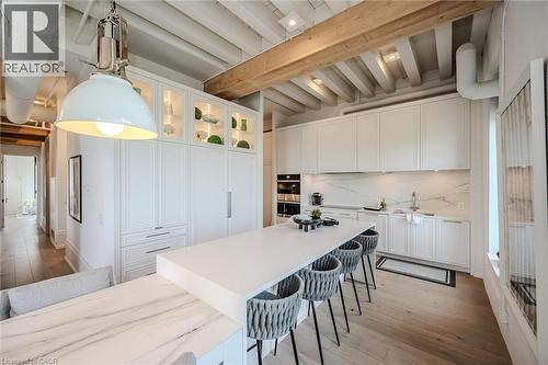 Kitchen with white cabinetry, light wood-type flooring, a breakfast bar, and beamed ceiling - 19 Guelph Avenue Unit# 308, Cambridge, ON - Indoor Photo Showing Kitchen