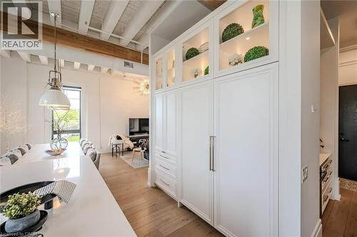Kitchen with hanging light fixtures, white cabinets, light wood-style floors, beam ceiling, and glass insert cabinets - 19 Guelph Avenue Unit# 308, Cambridge, ON - Indoor Photo Showing Dining Room