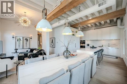 Kitchen featuring beamed ceiling, white cabinetry, decorative backsplash, hanging light fixtures, and light wood-type flooring - 19 Guelph Avenue Unit# 308, Cambridge, ON - Indoor