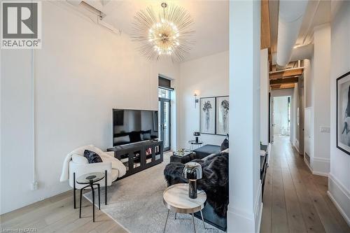Living area with light wood-style floors and hanging lights - 19 Guelph Avenue Unit# 308, Cambridge, ON - Indoor