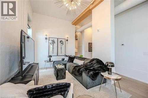 Living area featuring light wood finished floors, a chandelier, and a high ceiling - 19 Guelph Avenue Unit# 308, Cambridge, ON - Indoor