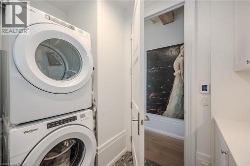 Laundry area with stacked washer and clothes dryer and dark wood-style floors - 19 Guelph Avenue Unit# 308, Cambridge, ON - Indoor Photo Showing Laundry Room