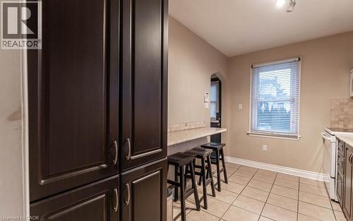 Kitchen featuring light tile patterned flooring, tasteful backsplash, dark brown cabinets, and white electric range - 501 Upper Wellington Street, Hamilton, ON - Indoor