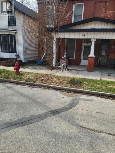 View of exterior entry with covered porch, brick siding, and board and batten siding - 54 Margaret Street, Hamilton, ON - Outdoor