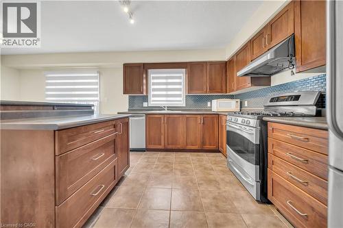 Kitchen featuring stainless steel appliances, wood finish cabinets, light tile patterned flooring, and tasteful backsplash - 51 Seabrook Drive, Kitchener, ON - Indoor Photo Showing Kitchen