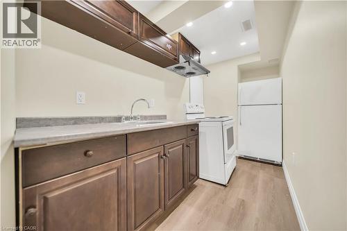 Kitchen with white appliances, light countertops, light wood-style flooring, range hood, and dark wood finish cabinetry - 51 Seabrook Drive, Kitchener, ON - Indoor Photo Showing Other Room