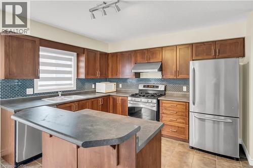 Kitchen with stainless steel appliances, light tile patterned flooring, a breakfast bar, backsplash, and track lighting - 51 Seabrook Drive, Kitchener, ON - Indoor Photo Showing Kitchen With Stainless Steel Kitchen