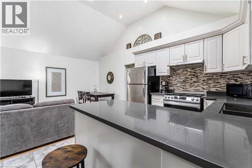 Kitchen featuring stainless steel appliances, tasteful backsplash, white cabinets, open floor plan, and a high ceiling - 74 Province Street N, Hamilton, ON - Indoor Photo Showing Kitchen