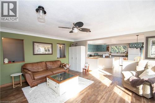 Living area featuring dark wood finished floors, a textured ceiling, ornamental molding, a ceiling fan, and a chandelier - 535 Mcdowell Road E, Simcoe, ON 