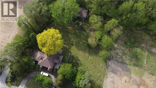 Aerial perspective showcasing a residential property with a brown-roofed structure, surrounded by mature trees and expansive green space - 535 Mcdowell Road E, Simcoe, ON 
