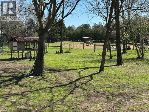 Expansive green space featuring scattered trees, a raised animal enclosure with a tiled roof, and a fenced paddock area - 535 Mcdowell Road E, Simcoe, ON 