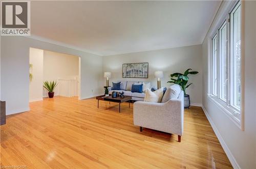 Main floor living room with gleaming, original hardwood flooring, bright windows and open to dining room - 66 Tupper Crescent, Kitchener, ON - Indoor Photo Showing Living Room