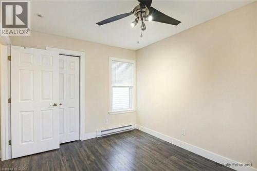 Unfurnished bedroom with dark wood-type flooring, baseboard heating, a closet, and ceiling fan - 27 Ashley Street, Hamilton, ON - Indoor Photo Showing Other Room