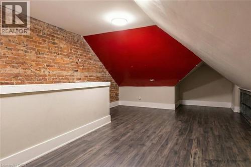 Additional living space with dark wood-type flooring, brick wall, and lofted ceiling - 27 Ashley Street, Hamilton, ON - Indoor Photo Showing Other Room