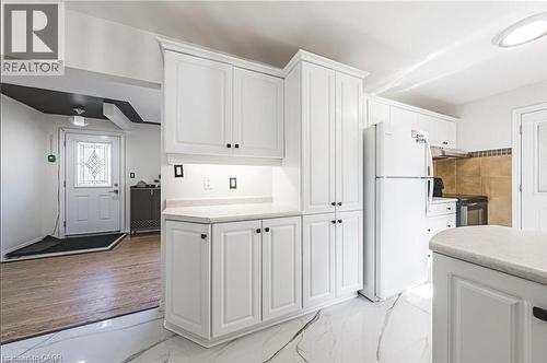 Kitchen with white cabinetry, freestanding refrigerator, light countertops, stainless steel electric range, and light marble finish flooring - 267 Erb Street E, Waterloo, ON - Indoor Photo Showing Laundry Room