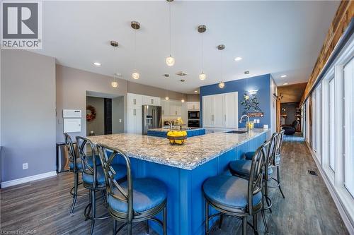 Kitchen featuring hanging light fixtures, high end fridge, light stone countertops, a breakfast bar, and dark wood finished floors - 1285 Cockshutt Road, Simcoe, ON - Indoor