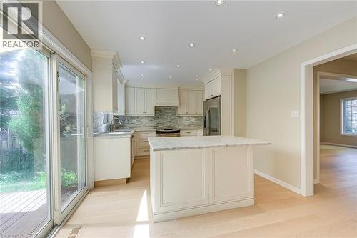 Kitchen featuring light stone counters, tasteful backsplash, stainless steel appliances, light wood-style flooring, and recessed lighting - 3037 Abernathy Way, Oakville, ON - Indoor Photo Showing Kitchen With Upgraded Kitchen