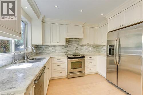 Kitchen featuring stainless steel appliances, light stone counters, recessed lighting, tasteful backsplash, and white cabinets - 3037 Abernathy Way, Oakville, ON - Indoor Photo Showing Kitchen With Double Sink With Upgraded Kitchen