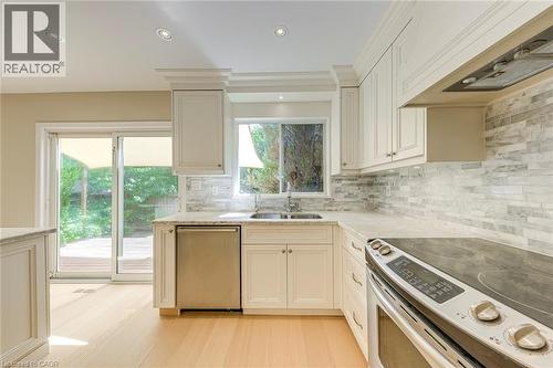 Kitchen with stainless steel appliances, recessed lighting, light stone counters, tasteful backsplash, and light wood finished floors - 3037 Abernathy Way, Oakville, ON - Indoor Photo Showing Kitchen With Double Sink With Upgraded Kitchen