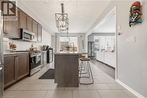 Kitchen with stainless steel appliances, a center island with sink, light stone counters, dark wood finish cabinets, and a kitchen bar - 105 Larry Crescent, Caledonia, ON - Indoor Photo Showing Kitchen With Stainless Steel Kitchen