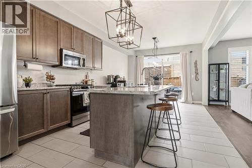 Kitchen with a kitchen island with sink, stainless steel appliances, a kitchen bar, suspended lighting, and wood tiled floors - 105 Larry Crescent, Caledonia, ON - Indoor Photo Showing Kitchen With Stainless Steel Kitchen With Upgraded Kitchen